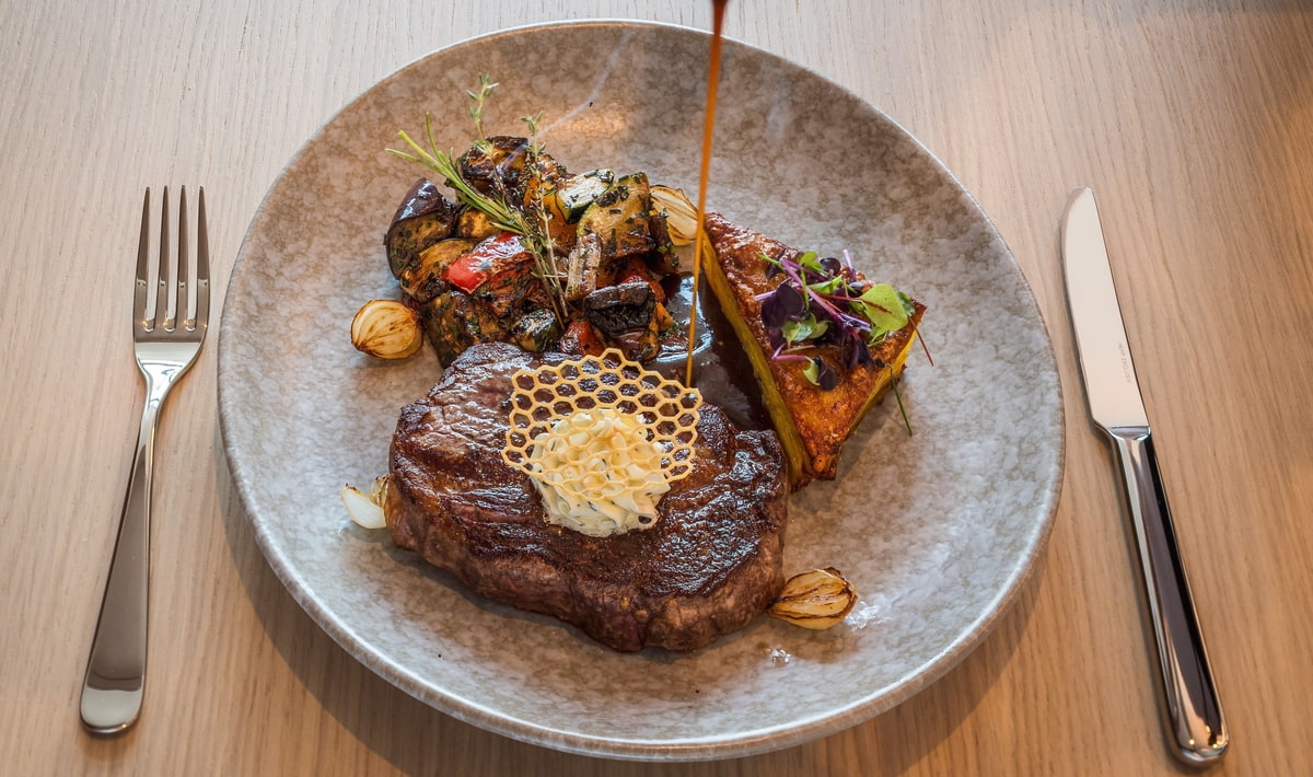 Saftig gebratenes Steak auf einem grau meliertem Teller, serviert mit Grillgemüse Saftig gebratenes Steak auf einem grau meliertem Teller, serviert mit Grillgemüse